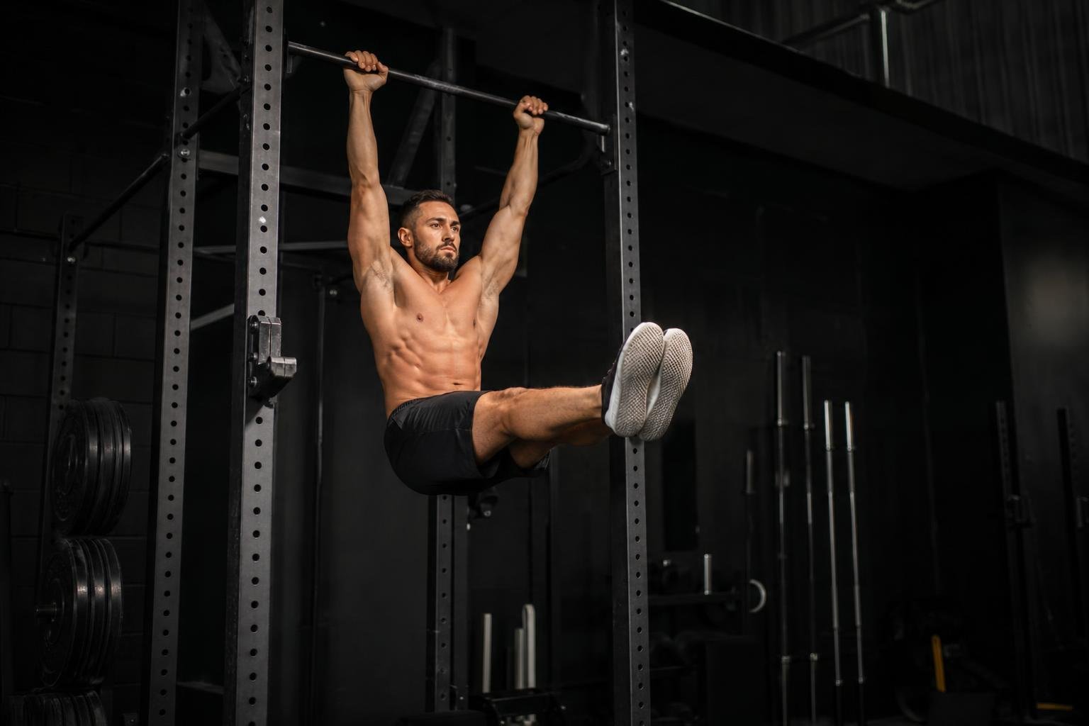Athlete performing advanced core exercises in a dark gym